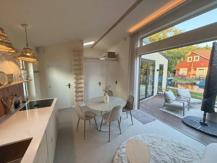 Woonkeuken met eettafel en open deuren naar terras en water